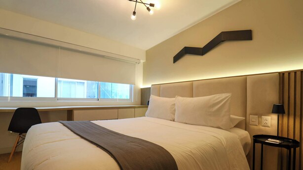 A modern hotel room with a large bed, a desk, and a window. - w* | Deluxe 1BR Duplex in the Heart of Barranco (Barranco)