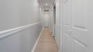 A hallway with white walls, wooden flooring, and white doors on the right. - The Shell: Walk-to-Beach Retreat (Long Beach)