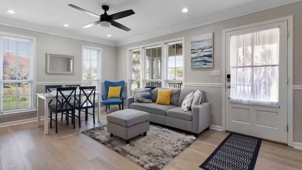 A spacious living room with a dining table, chairs, a sofa, and a ceiling fan. - The Shell: Walk-to-Beach Retreat (Long Beach)