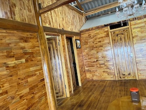 A room with wooden paneling, a chandelier, and a wooden table with a jar.