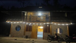 Un edificio con balcón, puerta de madera y un cartel sobre la entrada.