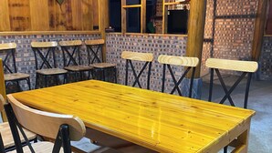 Un comedor de madera con una mesa larga y sillas, paredes de ladrillo y un techo rústico.