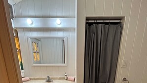 Une salle de bain avec deux lavabos, un miroir, un rideau de douche et des toilettes.