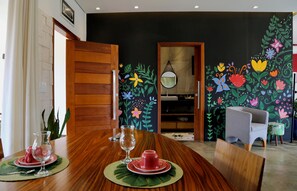 A dining area with a wooden table set for two, a vase, and a red cup.