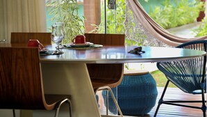 Un coin repas avec une table en bois, des chaises et une vue sur la verdure par une fenêtre.