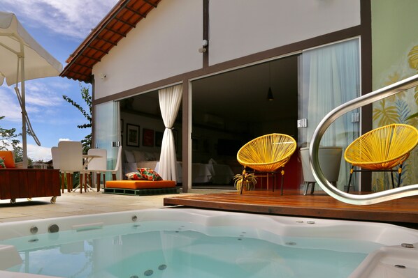 A pool area with a hot tub, yellow chairs, and a wooden deck.