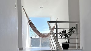 A staircase with a metal railing, a hammock, and a potted plant. - Spacious and comfortable apartment in a prime neighborhood in the city of Porto Seguro, Bahia. (Porto Seguro)