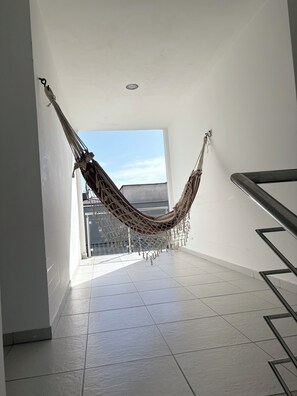 Een hangmat in een ruime, zonnige kamer met uitzicht op gebouwen.