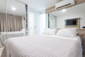 A modern hotel room with a large bed, a TV mounted on the wall, and a sliding door closet. - Ahead Ponta Negra #602 - Apartment by Carpediem (Natal)