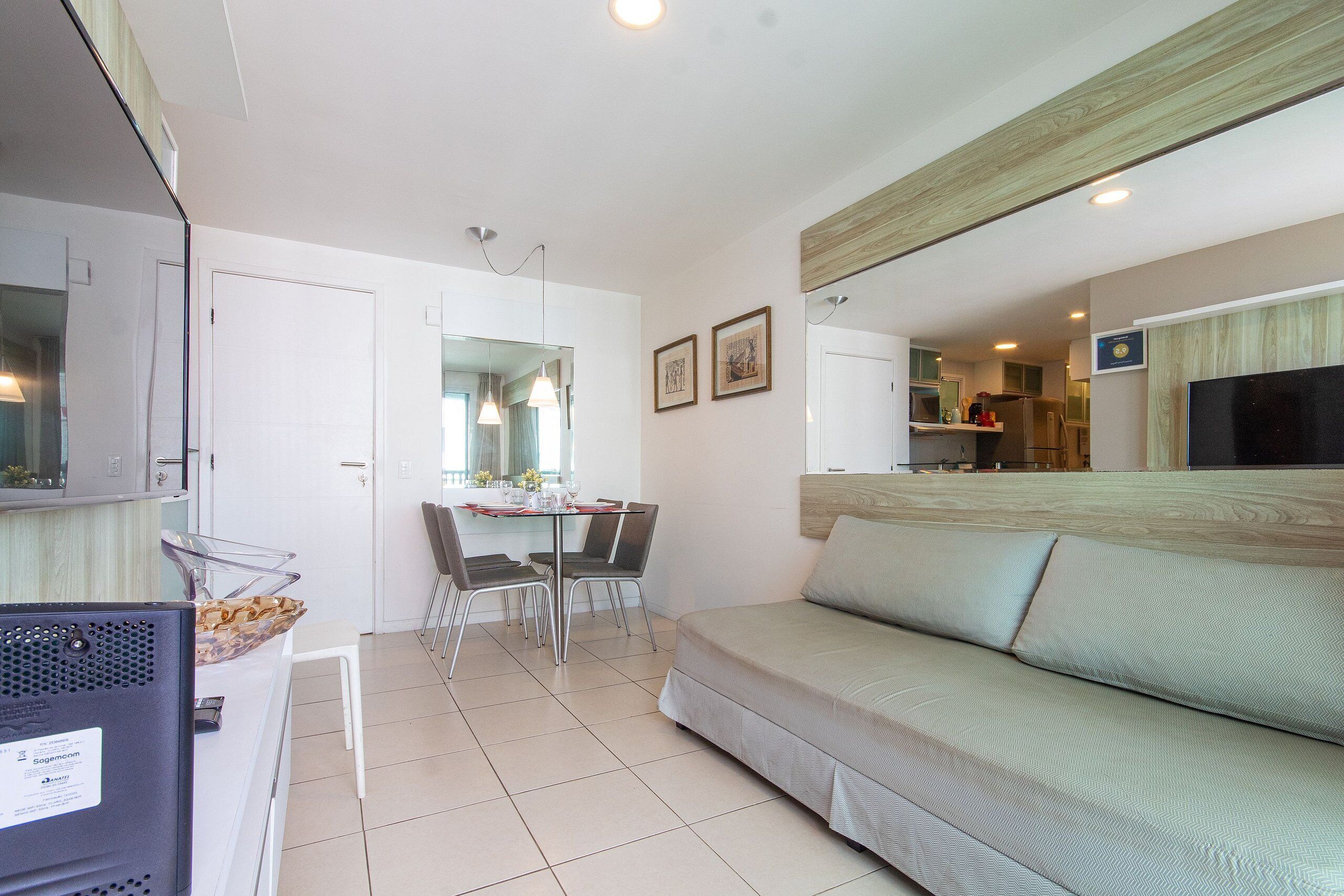 A modern living room with a sofa, a dining table with chairs, and a kitchen area in the background.