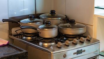 A stainless steel stove with four pots on burners and a digital clock displaying 11:34.