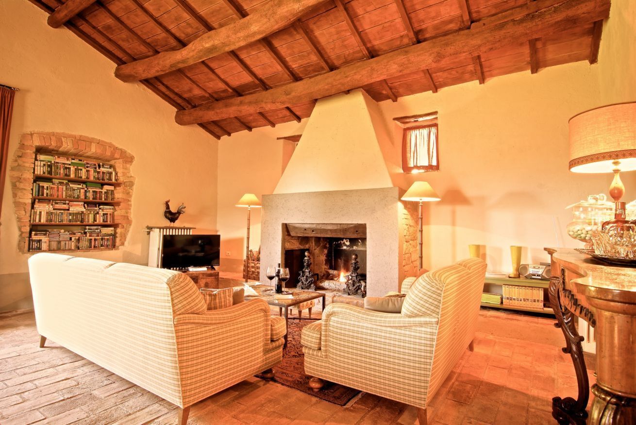 A cozy living room with a fireplace, wicker furniture, and a bookshelf.