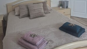 A neatly made bed with pillows, a bedside table with a lamp, and a door with a Wi-Fi sign. - Bed & Breakfast (Maxent)