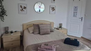A bedroom with a bed, bedside tables, a mirror, framed pictures, and a door. - Bed & Breakfast (Maxent)