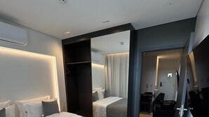 Et moderne hotelværelse med en stor seng, et walk-in closet og et siddeområde med et bord og stole.