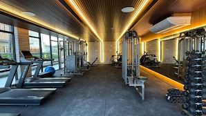 Et fitnesscenter med løbebånd, træningsmaskiner og håndvægte.
