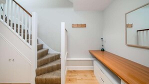 Eine Treppe mit hölzernem Geländer und Teppichstufen, die zu einer Zwischenebene führen.