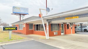 A building with a brick facade, a clear entrance sign, and a 'Clearance 7-0' sign above the entrance. - Deluxe Inn (Wilson)