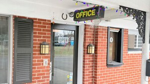A brick building with a black door labeled "OFFICE" and a sign above it. - Deluxe Inn (Wilson)