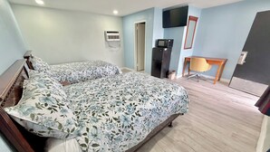 A bedroom with a bed, a desk, a television, and a microwave. - Deluxe Inn (Wilson)