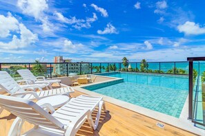 A rooftop pool with lounge chairs, a clear view of the ocean, and a tropical setting. - Rooftop #302 - Flat by the sea by Carpediem (Tamandaré)