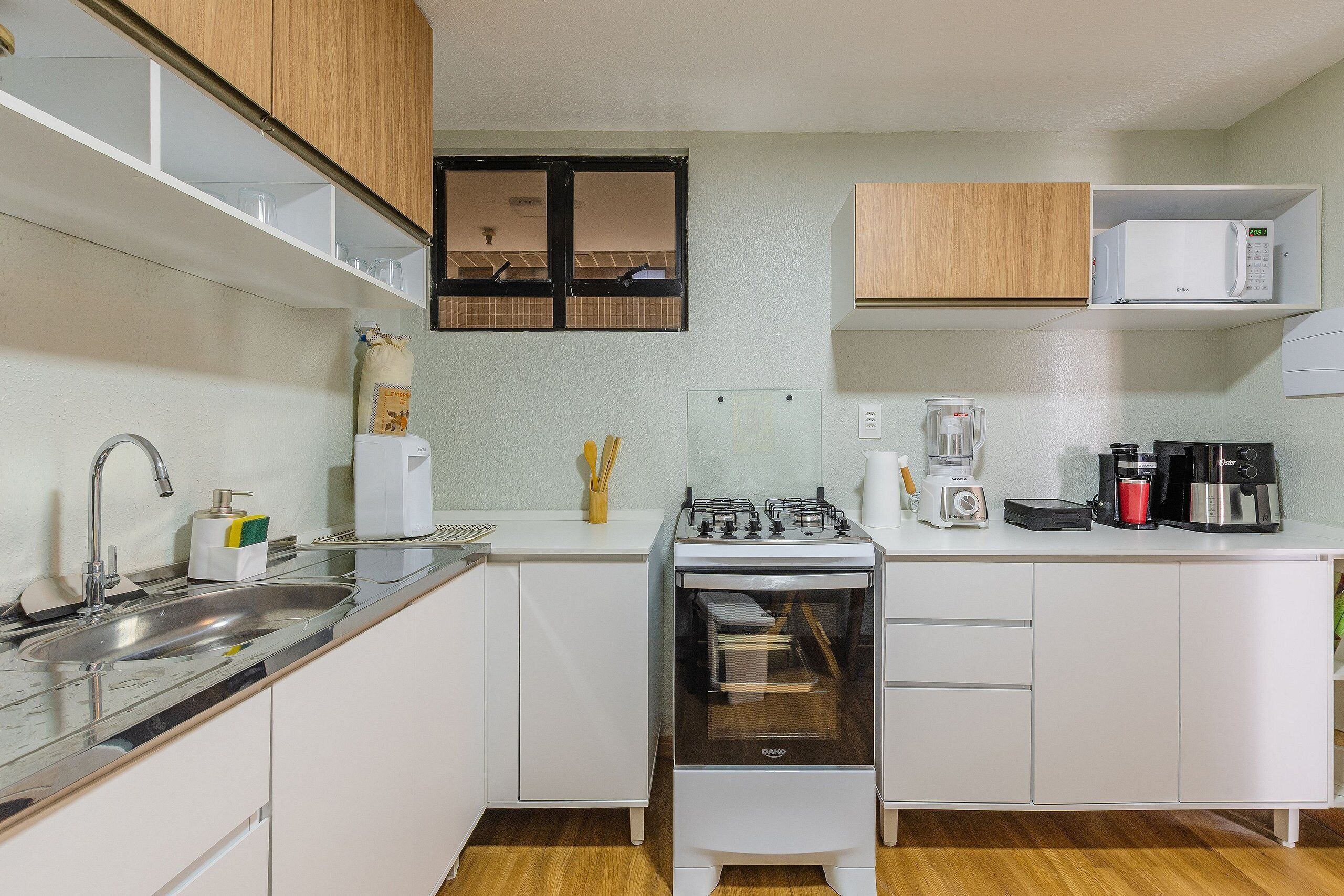 A compact kitchen with a gas stove, microwave, coffee maker, and a sink.