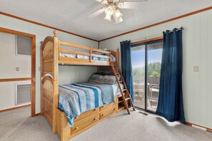 A bunk bed with a ladder, a ceiling fan, and a view to an outdoor patio. - Sandhill Unit: Oceanside| Dog Friendly (Duck)