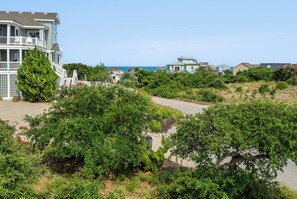 A multi-story building with balconies, surrounded by lush greenery and a clear view of the ocean. - Sandhill Unit: Oceanside| Dog Friendly (Duck)