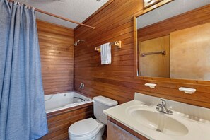 A wooden-paneled bathroom with a bathtub, toilet, and sink. - Sandhill Unit: Oceanside| Dog Friendly (Duck)