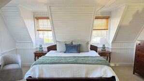 A bedroom with a large bed, two nightstands, a chair, and a dresser. - 06-Harbor Suite at The Castle Inn (Ocracoke)