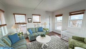 A cozy room with striped sofas, a round coffee table, and a patterned rug. - 12-Lighthouse Suite at The Castle Inn (Ocracoke)