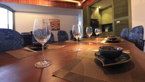 Una mesa de comedor dispuesta con copas de vino y cuencos, con sillas estampadas y techo de madera.