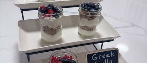 A dessert display with layered parfaits and a sign indicating 'Greek Vanilla Yogurt'.