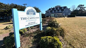 En skylt för värdshuset The Castle Inn vid Silver Lake, med ett stort hus i bakgrunden.