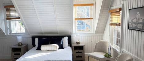 Une chambre à coucher avec un grand lit, une chaise, une table de chevet et une fenêtre avec des stores.
