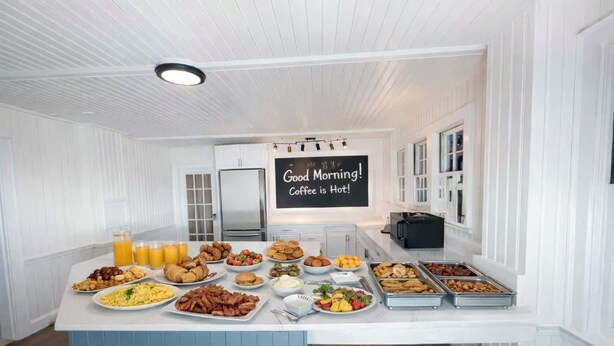 En frukostbuffé med ett varierat utbud av mat och en skylt med texten: ”God morgon! Kaffet är varmt!”