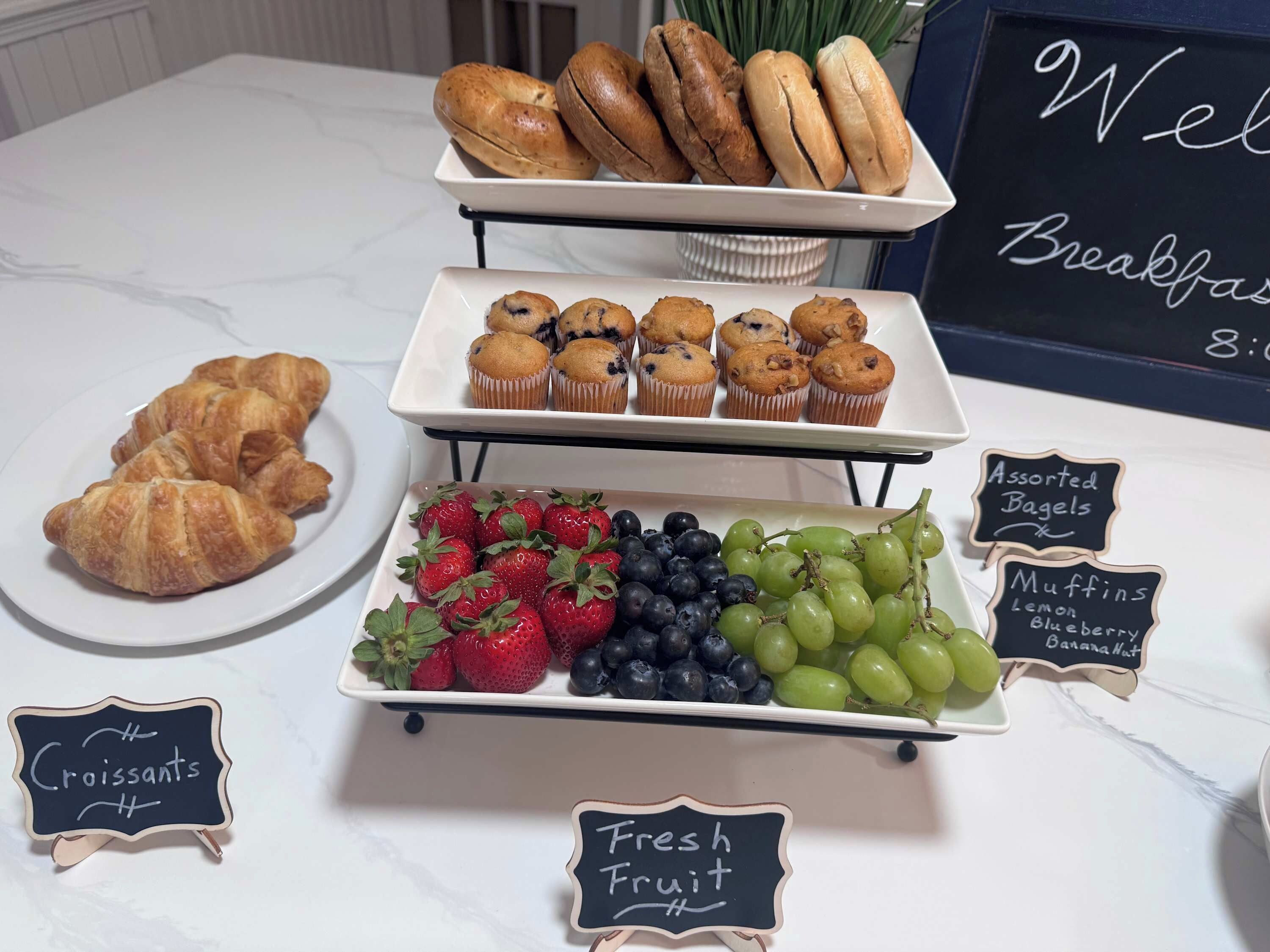 Un bufé de desayuno con croissants, muffins, bagels variados y fruta fresca.