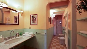 Un baño con lavamanos, espejo, toallero y piso a cuadros.