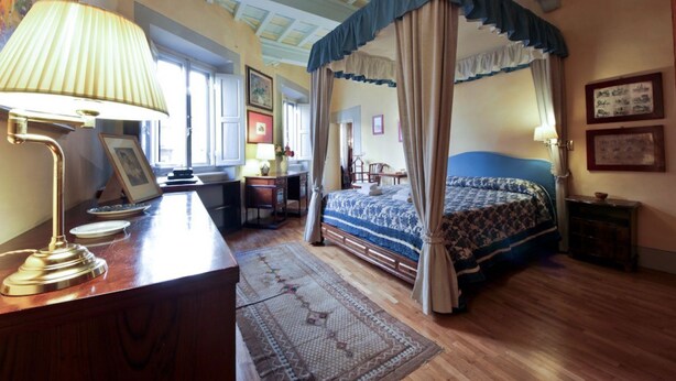 Un dormitorio con una cama con dosel, un escritorio con lámpara y una silla.