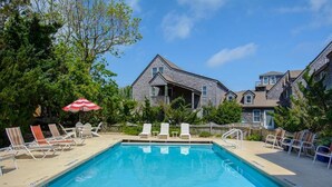A swimming pool with lounge chairs and an umbrella, surrounded by residential buildings. - 04-The Seashell Suite at The Castle Inn (Ocracoke)