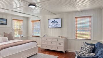 A bedroom with a bed, dresser, and a television displaying 'The Castle Inn at Silver Lake.'