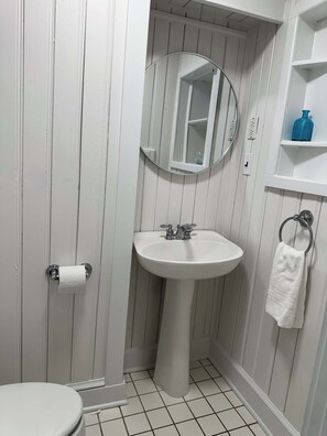 A bathroom with a white sink, a mirror, a toilet, and a towel rack.