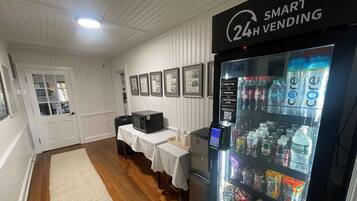 A room with a vending machine, a microwave, and a table with a white tablecloth.
