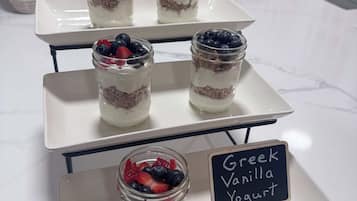 A dessert display with layered parfaits and a sign indicating Greek vanilla yogurt.