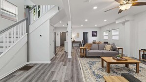 A modern living room with a staircase, a ceiling fan, and a dining area. - Mins to Children's Museum - Capitol Avenue Classic (Indianapolis)