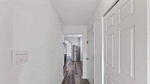 A hallway with white walls, a wooden floor, and a door on the right. - Mins to Children's Museum - Capitol Avenue Classic (Indianapolis)