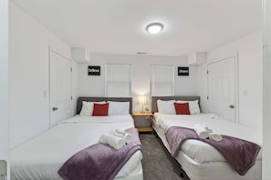 A hotel room with two beds, a nightstand, and a ceiling light.