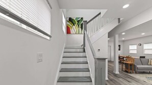 A staircase leading to a living area with a dining table and a sofa. - Mins to Children's Museum - Capitol Avenue Classic (Indianapolis)