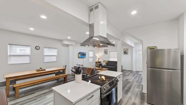 A modern kitchen with a central island, stainless steel appliances, and a dining area with a bench. - Mins to Children's Museum - Capitol Avenue Classic (Indianapolis)
