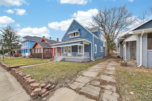 A row of single-story houses with a front porch, a brick walkway, and a clear sky.